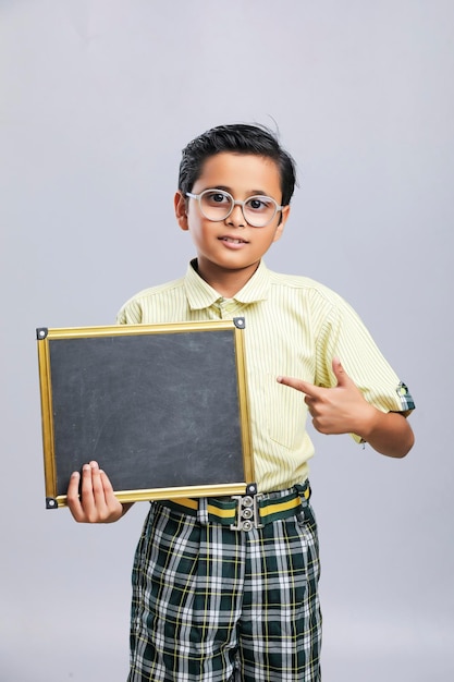 Indian school boy showing black board with copy space