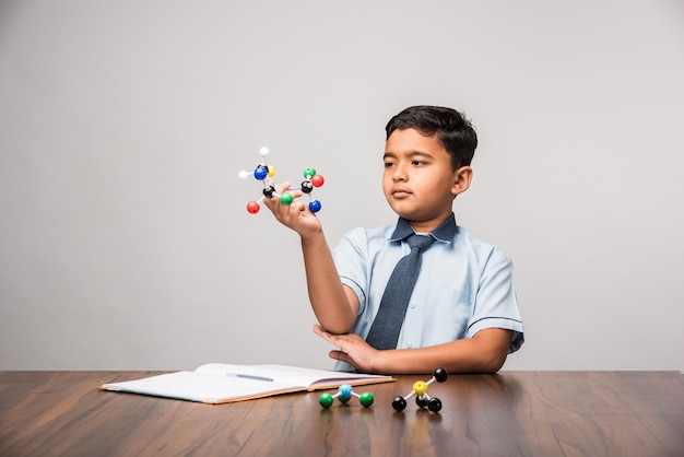 Indian school kid or science student Using Molecular Model Kit for studying physics, selective focus