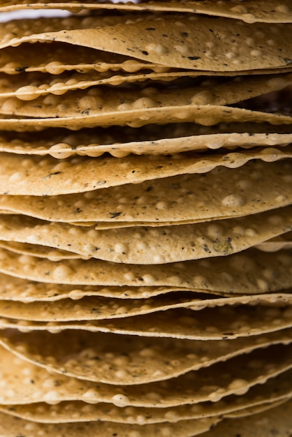 Indian snacks, Pile of deep fried or roasted Mung Urad dal crackers or papad which is a side dish in lunch and dinner. Served in a cane basket or plate with Coriander leaf.