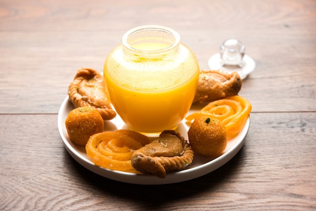 Indian sweets Gujiya, motichoor laddu and jalebi and Clarified butter or Indian desi ghee in a jar, selective focus