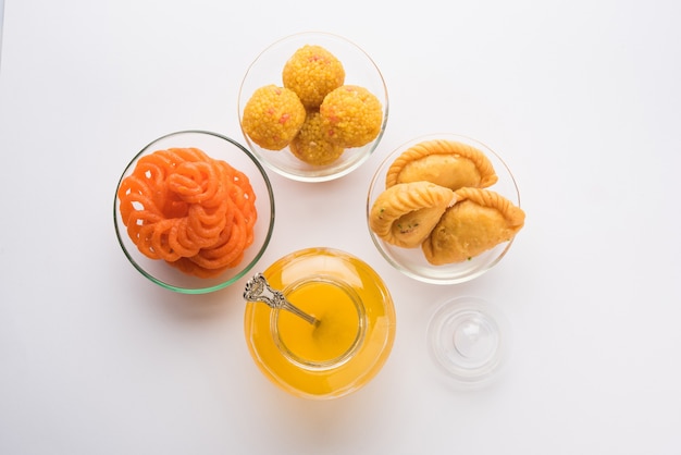 Indian sweets Gujiya, motichoor laddu and jalebi and Clarified butter or Indian desi ghee in a jar, selective focus