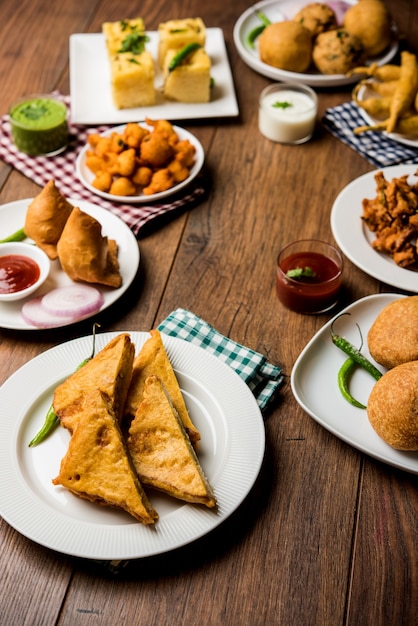 Indian Tea time snacks  in group includes Veg Samosa, Kachori, kachaudi, aloo bonda, khaman dhokla, bread, onion,chilli and moong pakora, pakoda, bhaji, bhajji,Bhajiya,bajji with sauces