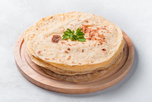 Indian traditional chapati tortillas with fresh herbs closeup on a gray background