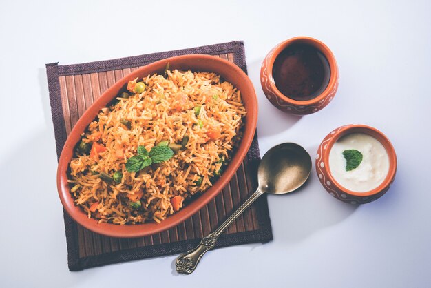 Indian Vegetable Pulav or Biryani made using Basmati Rice, served in terracotta bowl. selective focus