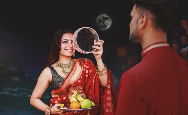 Photo indian woman celebrating karva chauth by looking at her husband at night