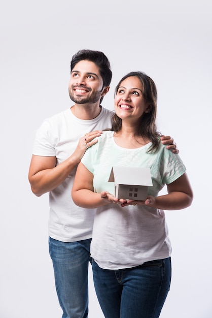 Indian young family couple and real estate concept - buying or rental, standing against white background