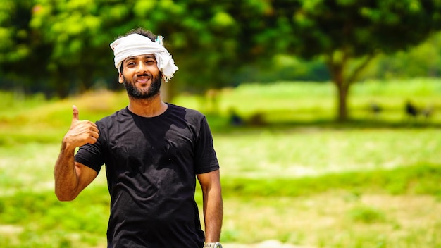 Indian young farmer giving thumbs up handsome boy with his land in village