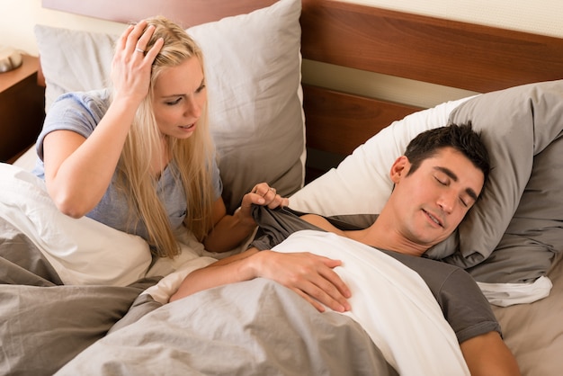 Indifferent man sleeping in bed next to his partner