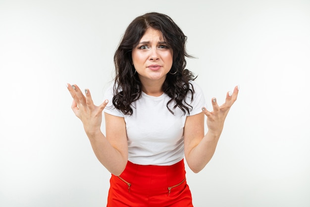 Indignant brunette girl in a white tank top fed up on a white studio background.