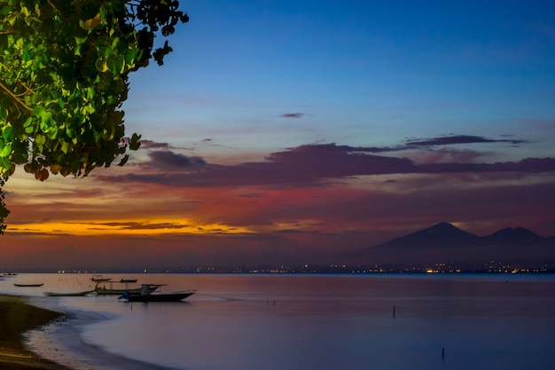 Indonesia. Beach after sunset and tied empty boats. The lights of the city on the other side of the bay