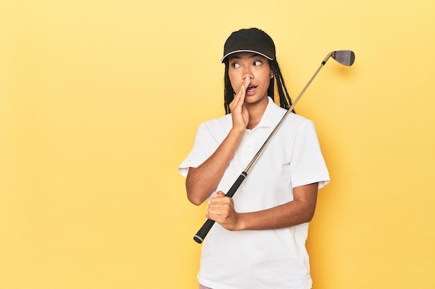 Photo indonesian female golfer on yellow backdrop is saying a secret hot braking news and looking aside