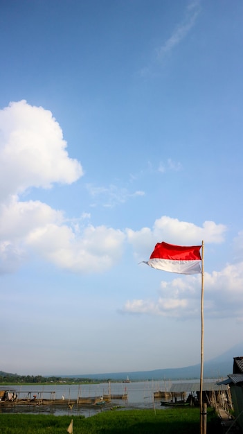 Indonesian flag tied to a bamboo pole and exposed to the wind during the day with a blue sky background