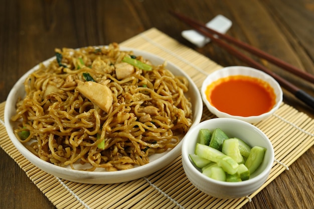 Indonesian fried noodles served with acar timun on the white plate and wooden background