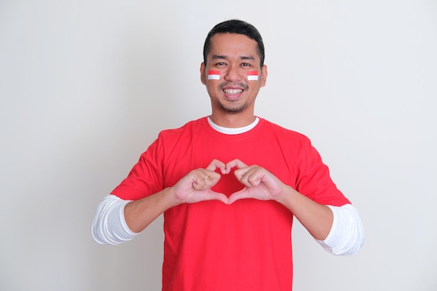 Indonesian man looking camera with love heart finger siymbol on chest