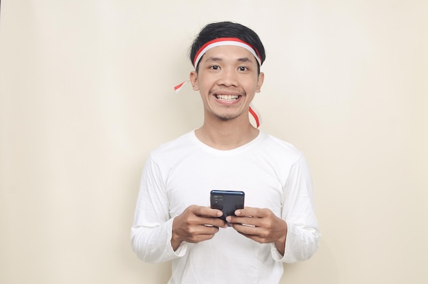 Indonesian man smiling while holding a mobile phone during independence day celebration