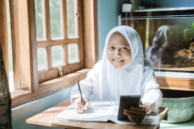 Indonesian schoolgirl studying homework during her online lesson at home