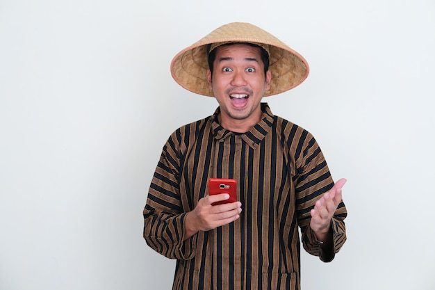 Indonesian traditional farmer shoing excited expression while holding mobile phone