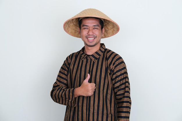 Indonesian traditional farmer smiling at camera ang give thumb up