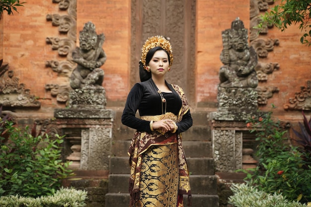 Indonesian woman wearing balinese kebaya and woven cloth against temple