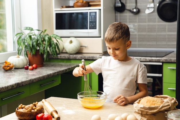 Indoor activity. Young child boy cooking in the kitchen. Doing cakes or biscuits