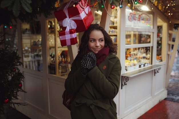 Indoor portrait of beautiful girl in red winter jacket who's blowing snow on Christmas Fair