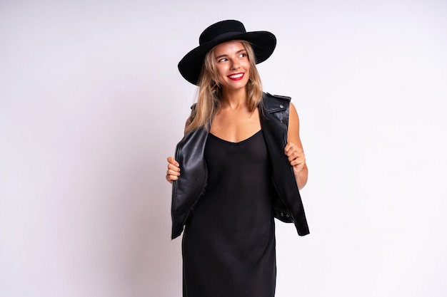 Indoor portrait of stylish woman wearing black dress and hat having fun, rock n roll style.