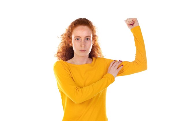 Indoor portrait of young redhead female with wavy long hair positively shows her muscles and smile