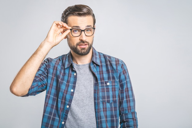 Indoor shot of amazed excited man touching his glasses.