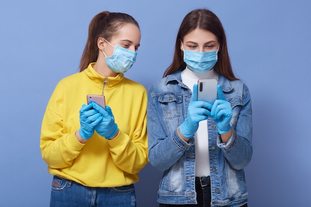 Indoor shot of attentive concentrated two women holding their smartphones