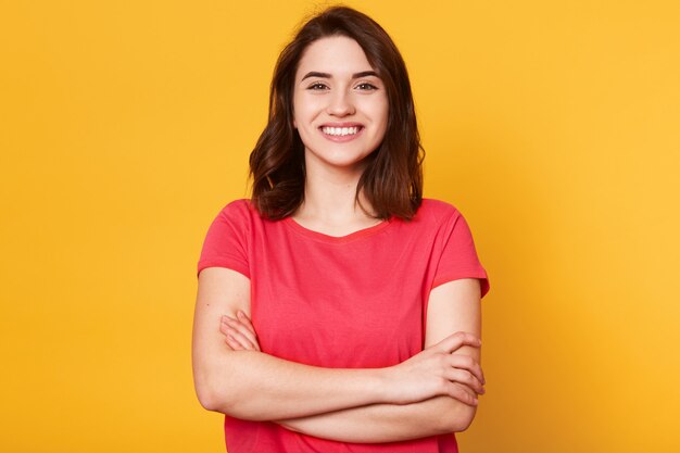 Indoor shot of magnetic beautiful young girl standing with folded arms