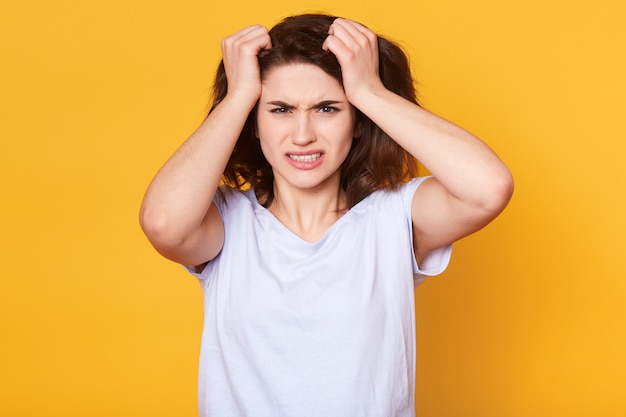 Indoor studio shot of stressed exhausted woman having unpleasant facial expression