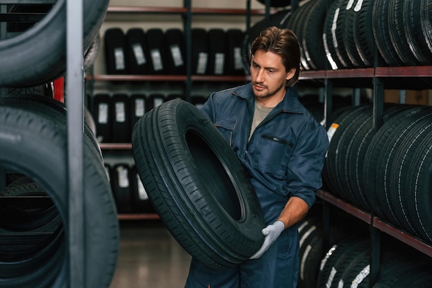 Indoors holding tire Man is in the tire fitting car service