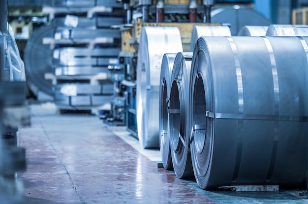 Industrial background. Big size steel coil stored inside industrial warehouse, blue toned image.