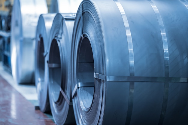 Industrial background. Big size steel coil stored inside industrial warehouse, blue toned image.