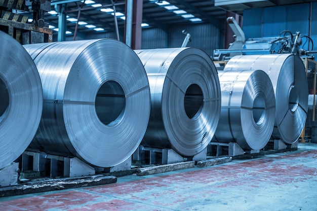 Industrial background. Big size steel coil stored inside industrial warehouse, blue toned image.