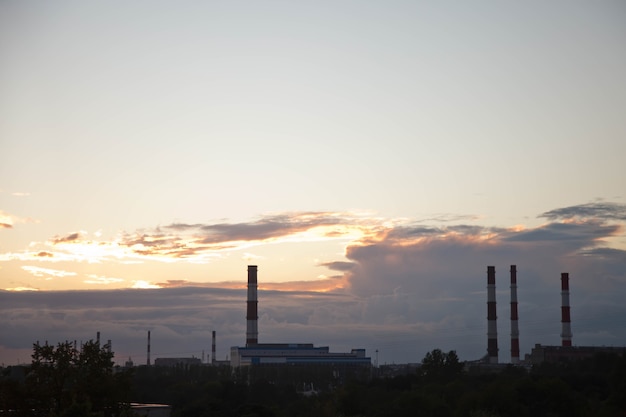 Industrial brick chimneys against textured sunset sky. Concept of production and environmental pollution in city. Copyright space for site