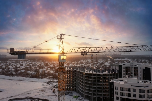 Industrial cranes at construction site with sunset sky background