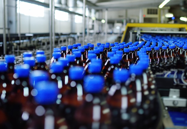 Industrial food production of beer. Plastic beer bottles on a conveyor belt in the background of a brewery