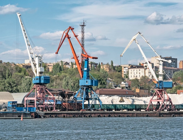 Industrial harbor cranes loading bulk weight into railway wagons in sea port