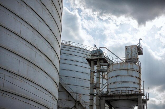 Industrial Metal Staircase on Storage Tank Against Cloudy Sky