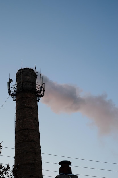 Industrial pipe and smoke against the sky