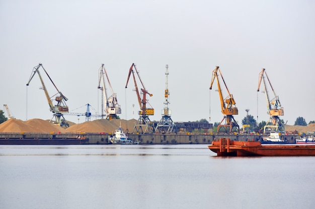 Industrial river waterscape with cargo terminal and mooring tugboats and bulk barges