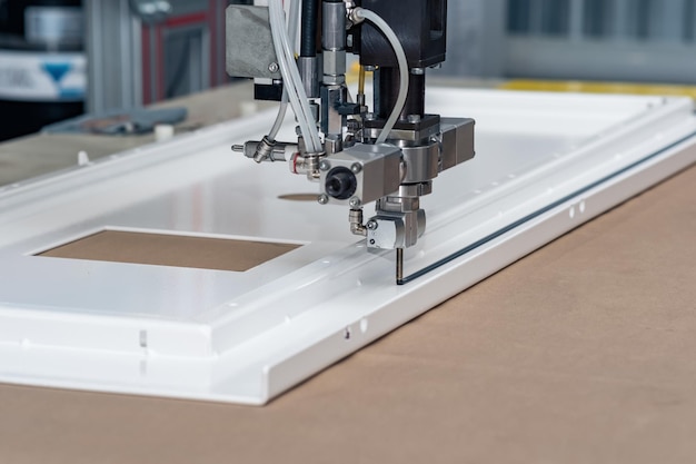 Industrial robotic dosing dispenser machine applies a hardening sealant to the metal door blank