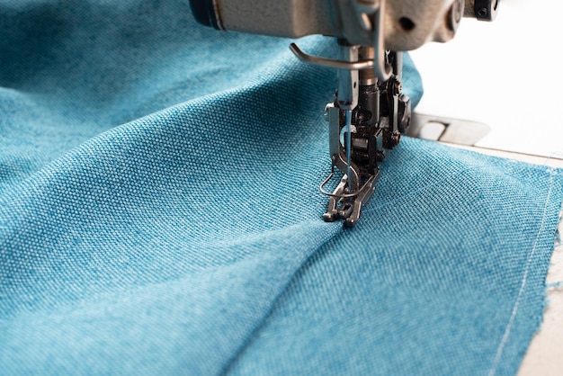 Photo industrial sewing machine blue fabric working place manufacture clothes handmade textile industry