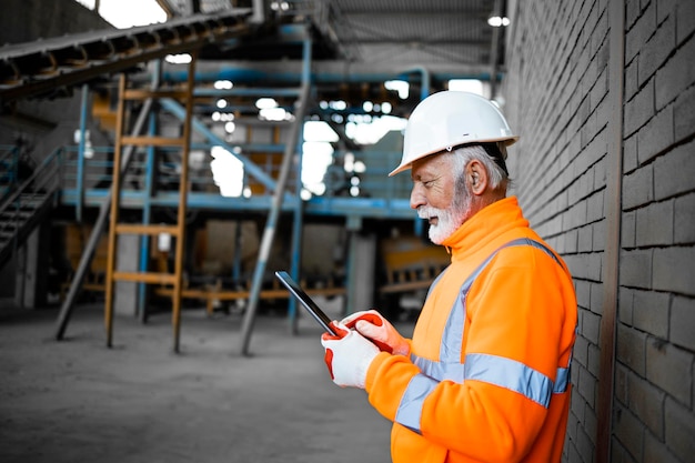 Industrial supervisor worker checking production results on tablet computer in factory.