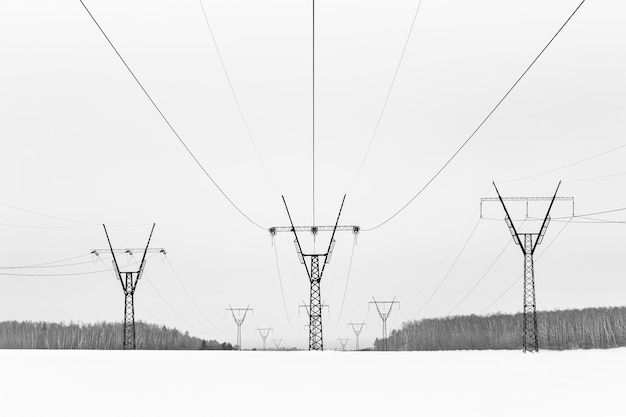 Industrial winter landscape with three power lines stretching through snow covered field Russia