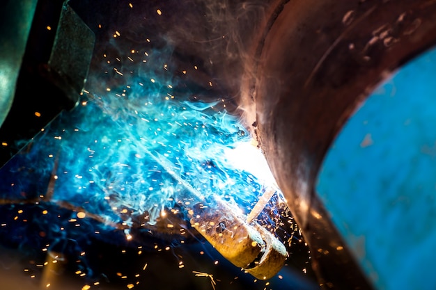 Photo industrial worker at the factory welding closeup