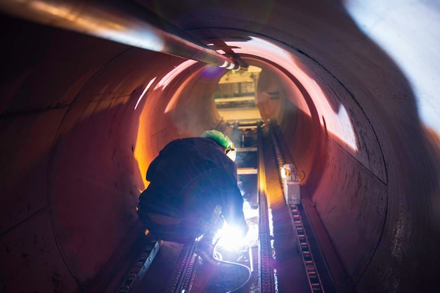 Industrial worker welding metal sparks inside piping construction