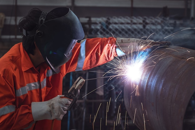 Industrial worker with protective mask welding steel structure in a factory