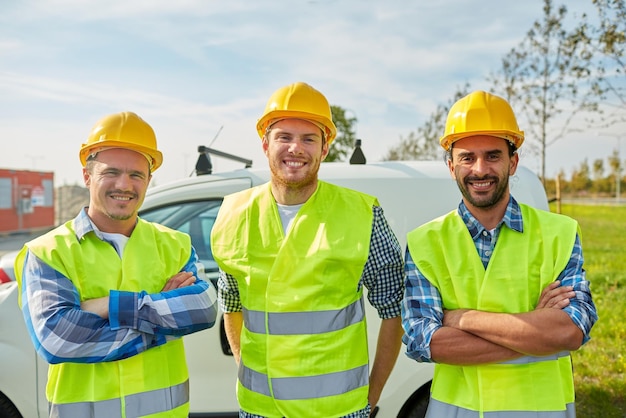 industry, building, construction and people concept - happy male builders in high visible vests outdoors